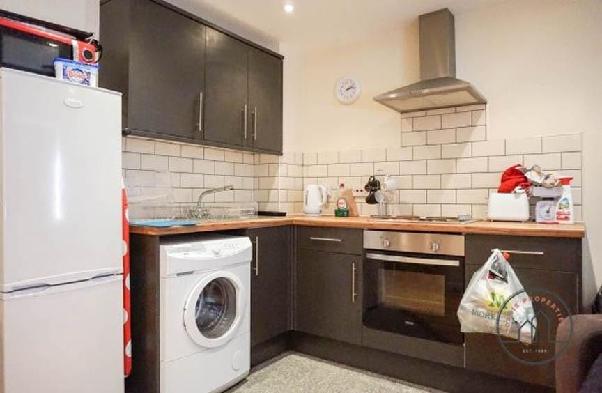 Modern fitted kitchen with dark cabinets, stain...