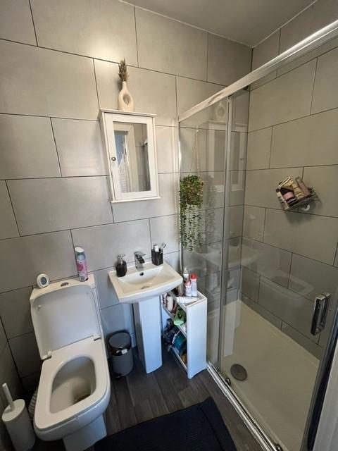 Modern tiled bathroom with a corner glass showe...