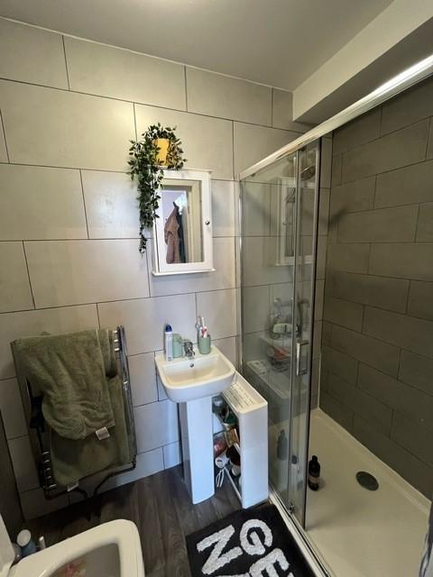 Modern bathroom with tiled walls, a corner show...