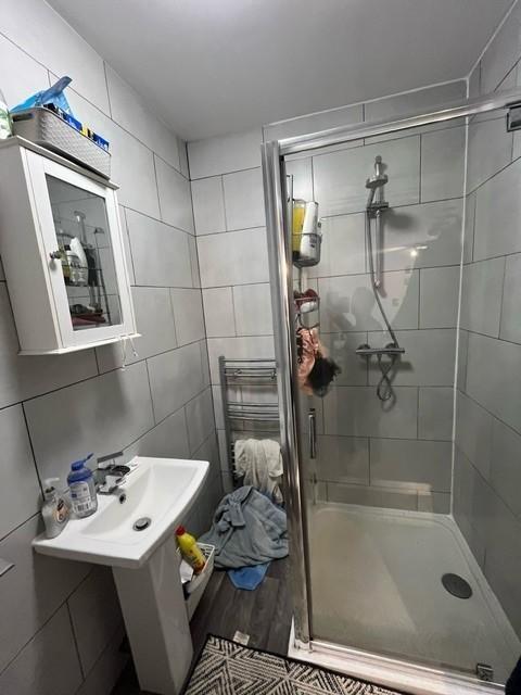 Modern tiled bathroom with a glass-enclosed sho...