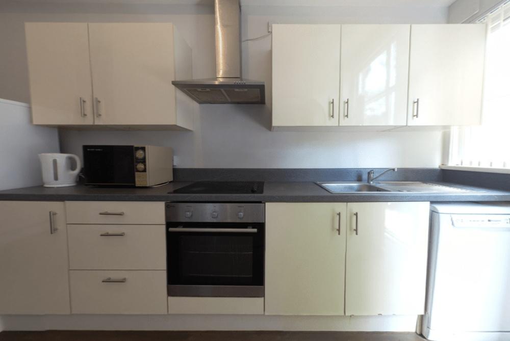 Modern fitted kitchen with white cabinetry, int...