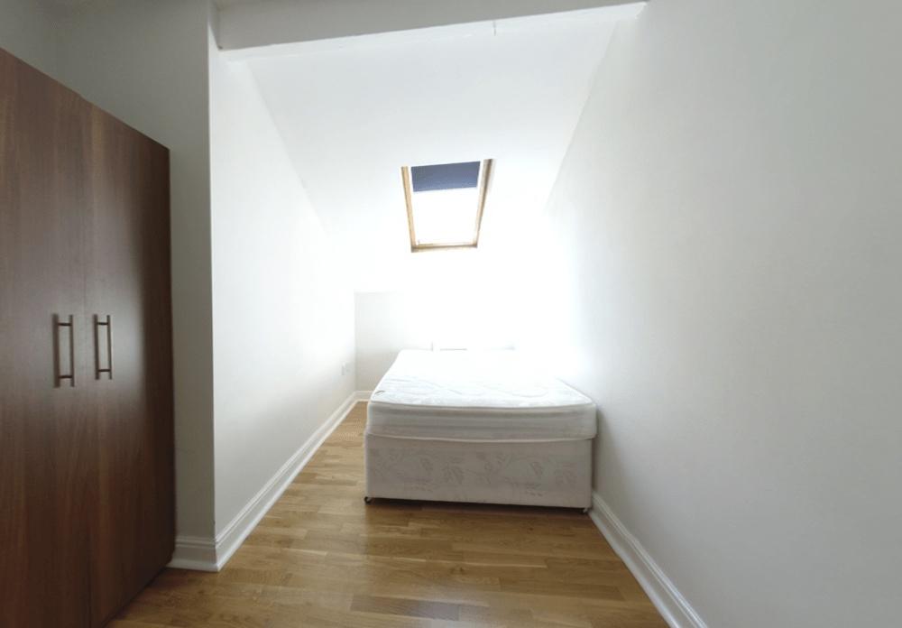 Bright attic-style single bedroom with a skylig...