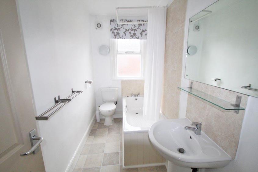 Bright, modern bathroom with a bathtub and over...