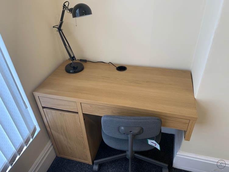 Compact furnished workspace with a light wood d...