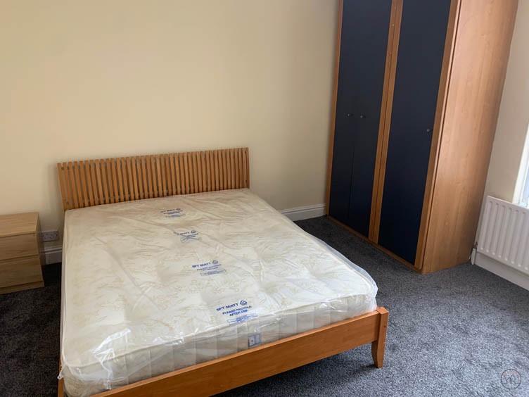 Neat double bedroom with a wooden bed frame, ma...
