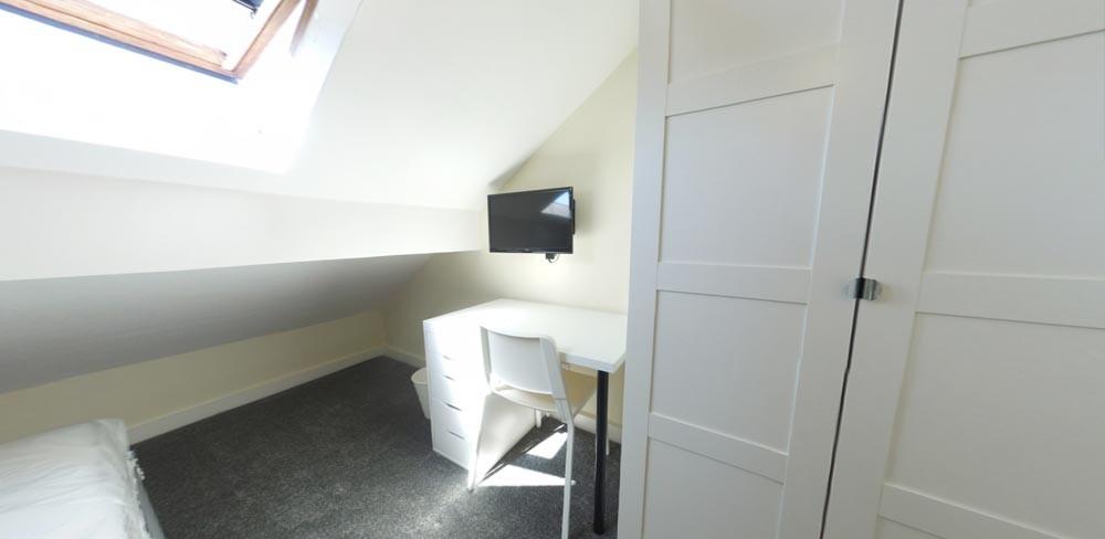 Bright attic-style single bedroom with a skylig...