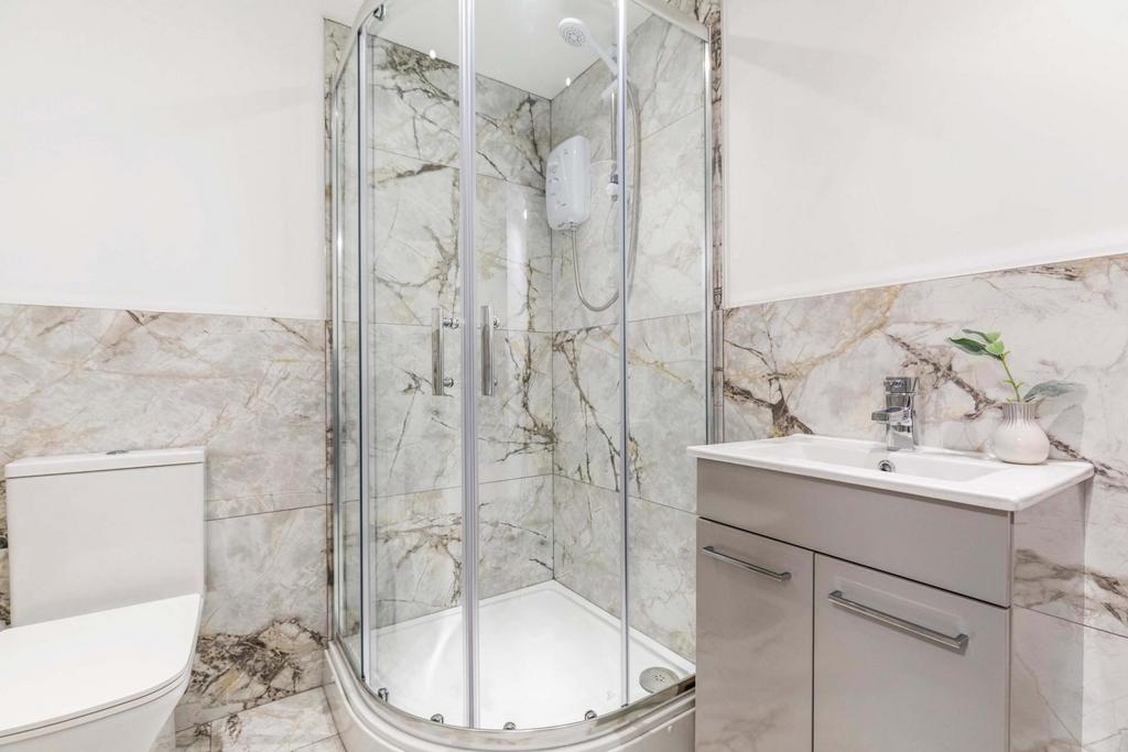 Bright, modern bathroom featuring a curved glas...