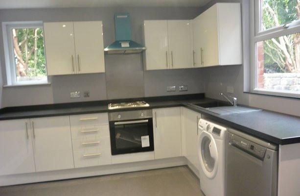 Modern U-shaped kitchen with white cabinets, da...