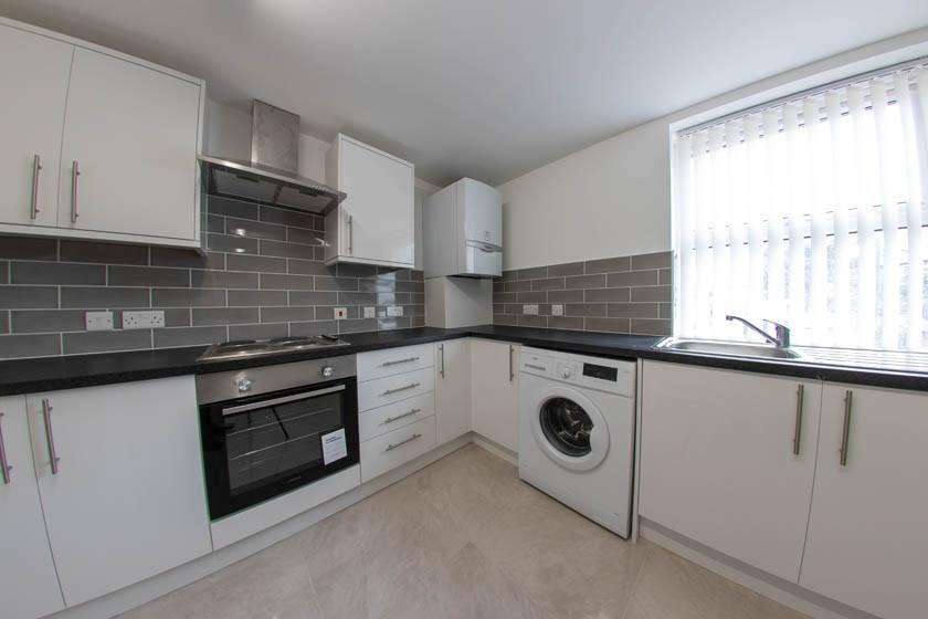 Bright modern kitchen with white cabinetry, int...