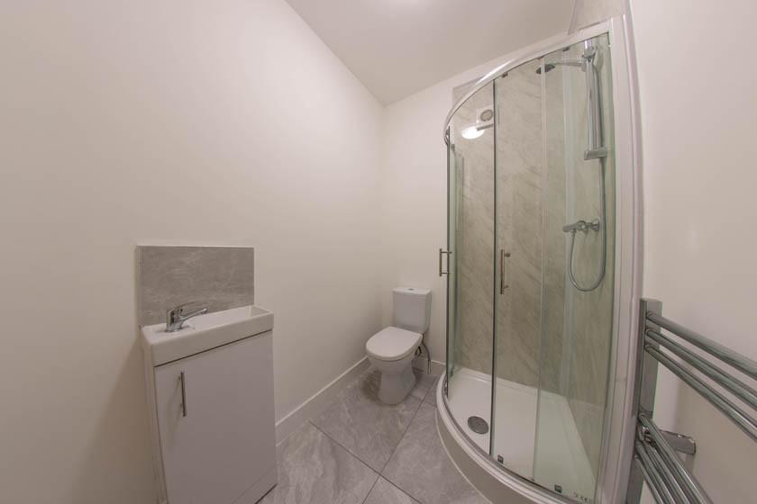 Bright, modern bathroom with a curved glass sho...