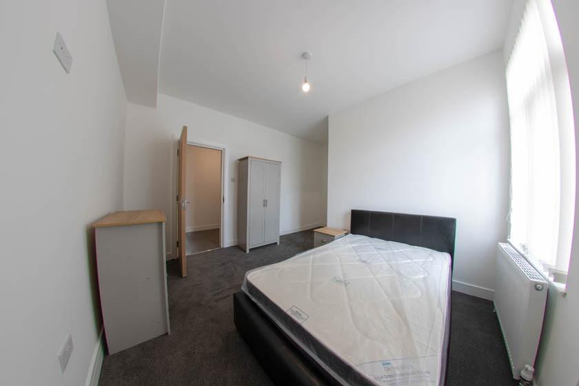 Bright, simply furnished bedroom with a double ...