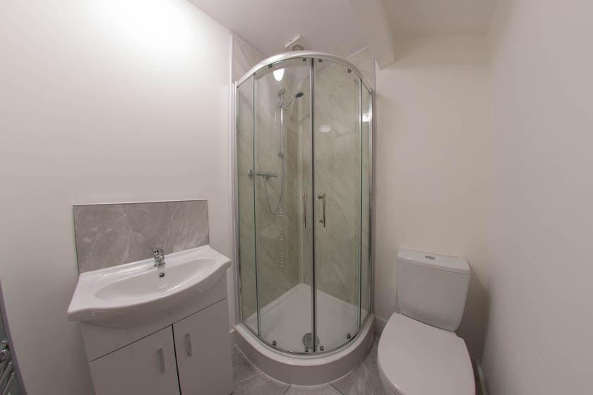 Compact modern bathroom with a corner glass sho...