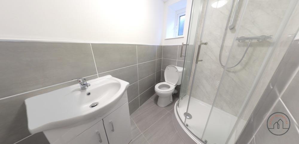 Bright, modern bathroom with a curved glass sho...