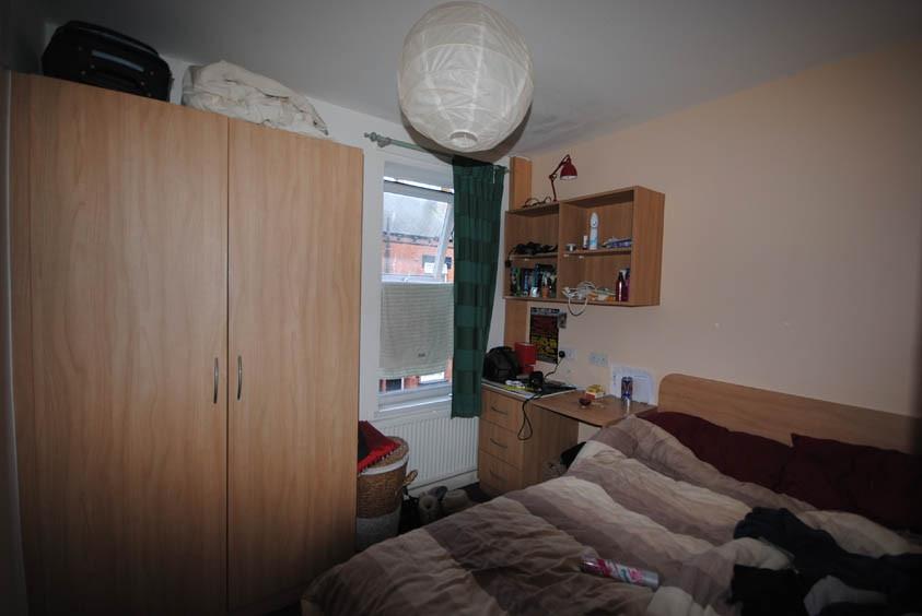 Cozy furnished bedroom with a wardrobe, desk, s...