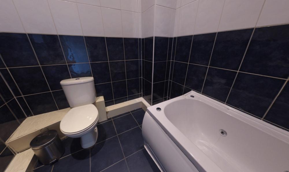 Modern tiled bathroom with a full-size bathtub,...