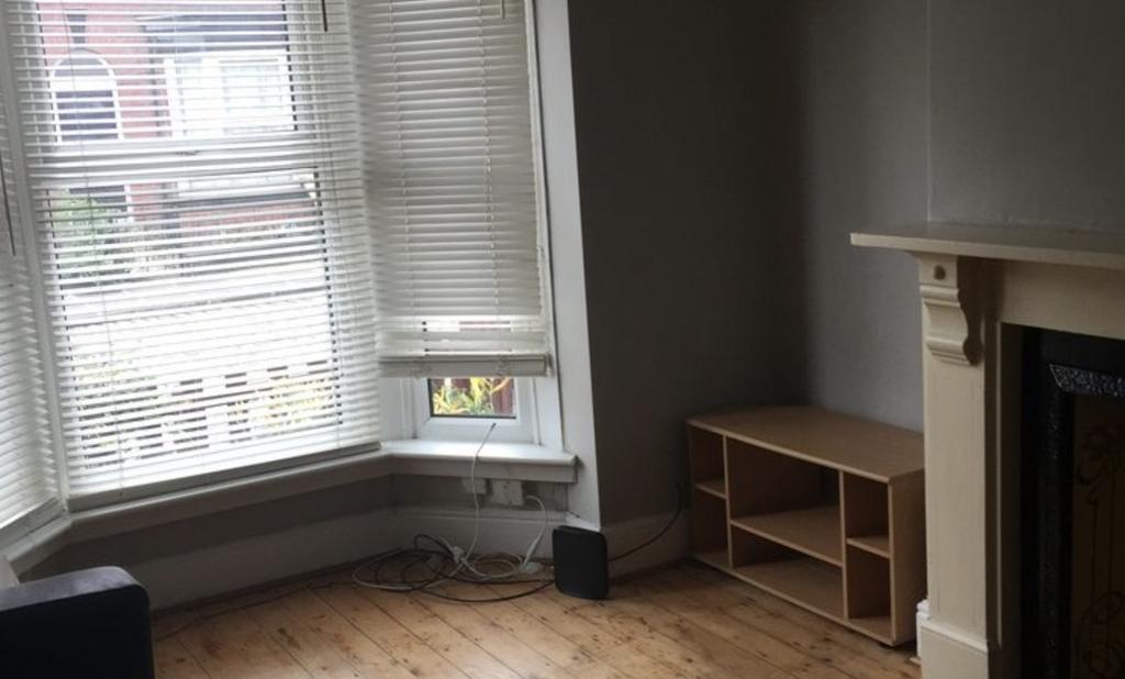 Bright living room with a large bay window lett...