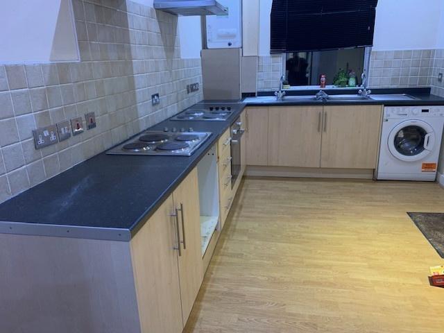 Modern fitted kitchen with light wood cabinets,...