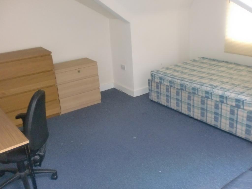 Simple furnished bedroom with a single bed, des...
