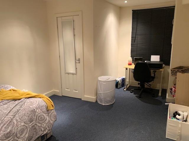 Neatly presented bedroom with a made bed, study...