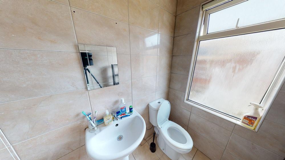 Bright tiled bathroom with a pedestal sink, mir...