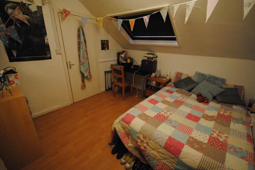 Cozy double bedroom with a patterned quilted be...