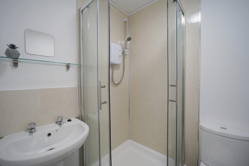 Bright, modern bathroom with a corner glass sho...