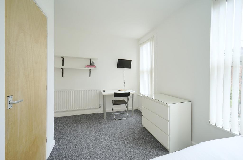 Bright, simply furnished bedroom with neutral d...