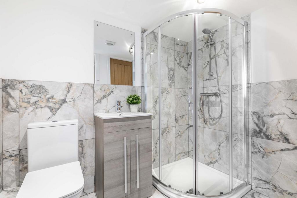 Bright, modern bathroom featuring a corner glas...