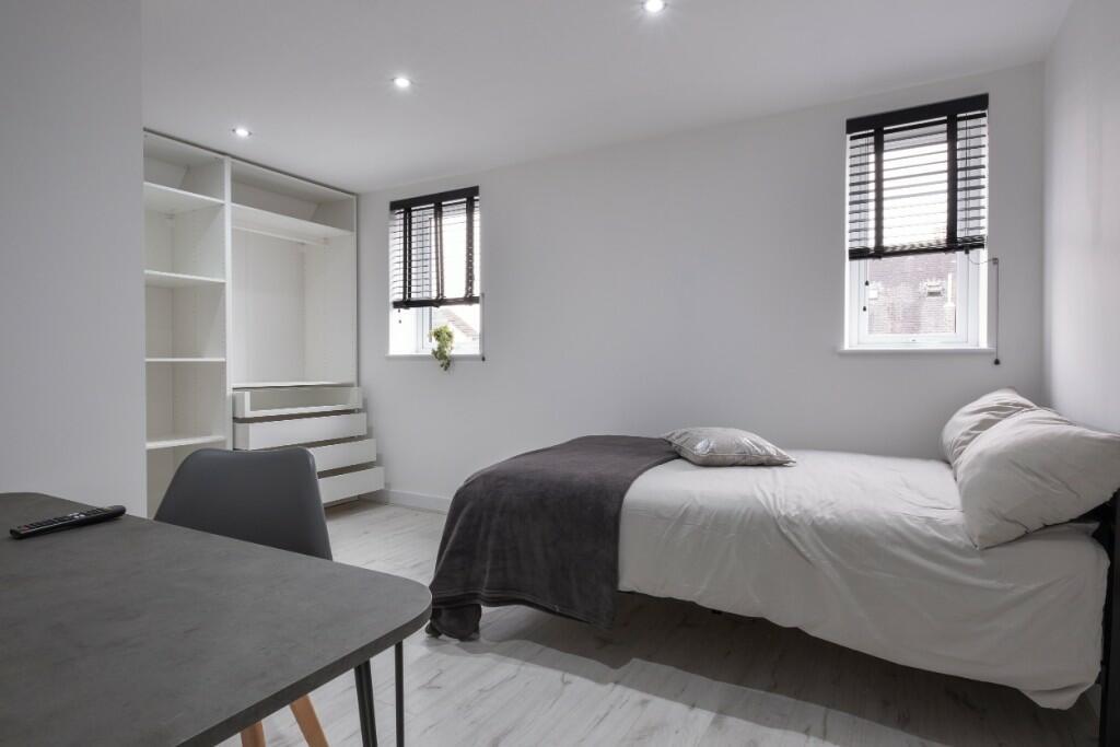 A neat and modern single bedroom featuring a co...
