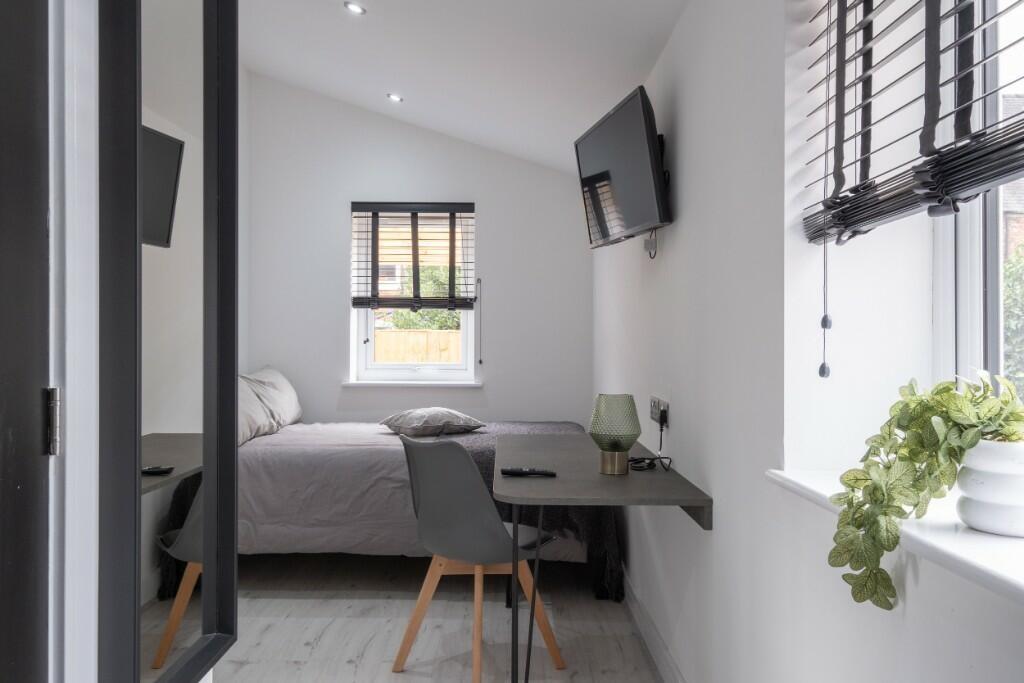 A neatly arranged single bedroom featuring a co...