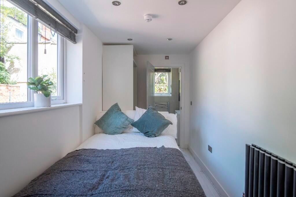 A bright, neatly arranged double bedroom featur...