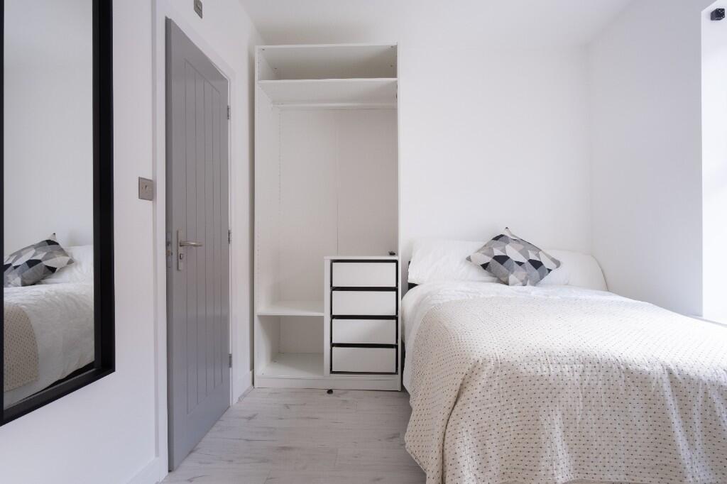 A bright and tidy single bedroom featuring a co...