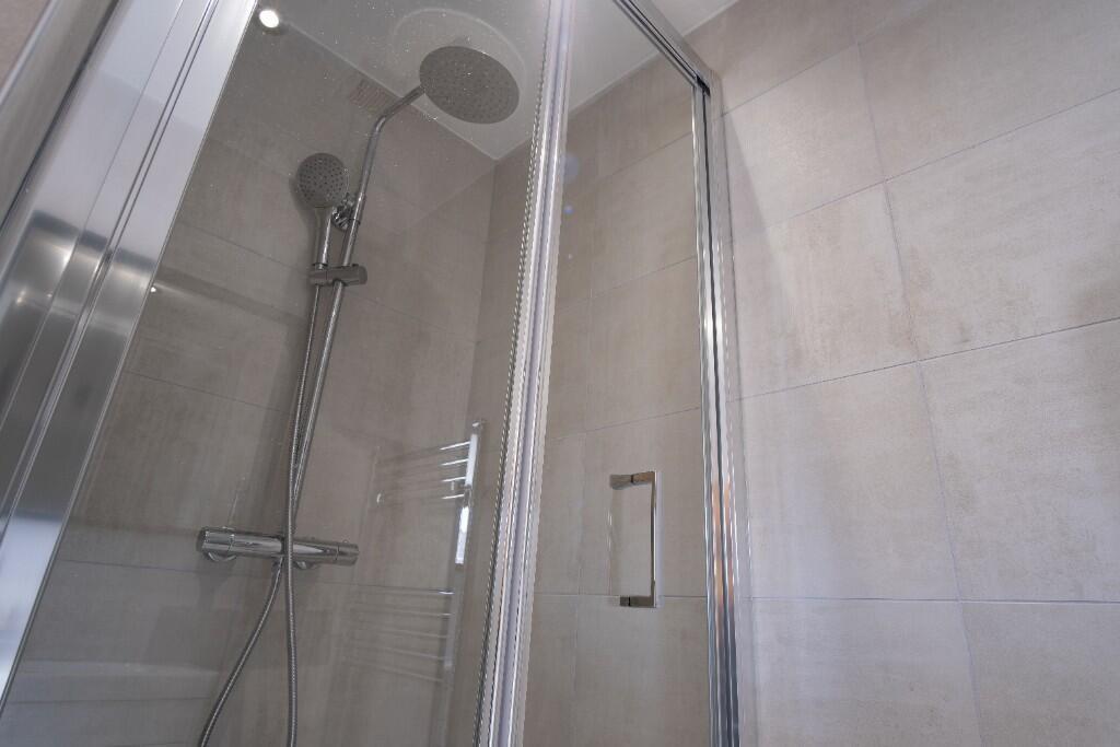 A modern bathroom featuring a spacious shower w...