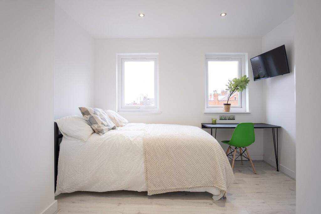 Bright and airy bedroom featuring two clean win...