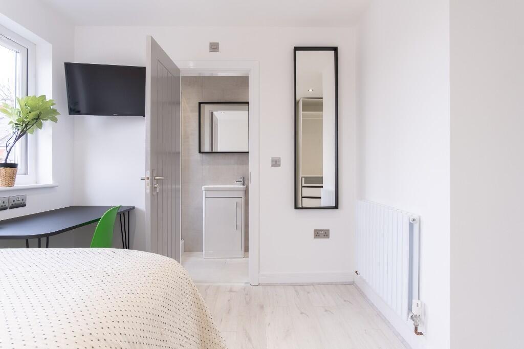 A bright and tidy bedroom featuring a comfortab...
