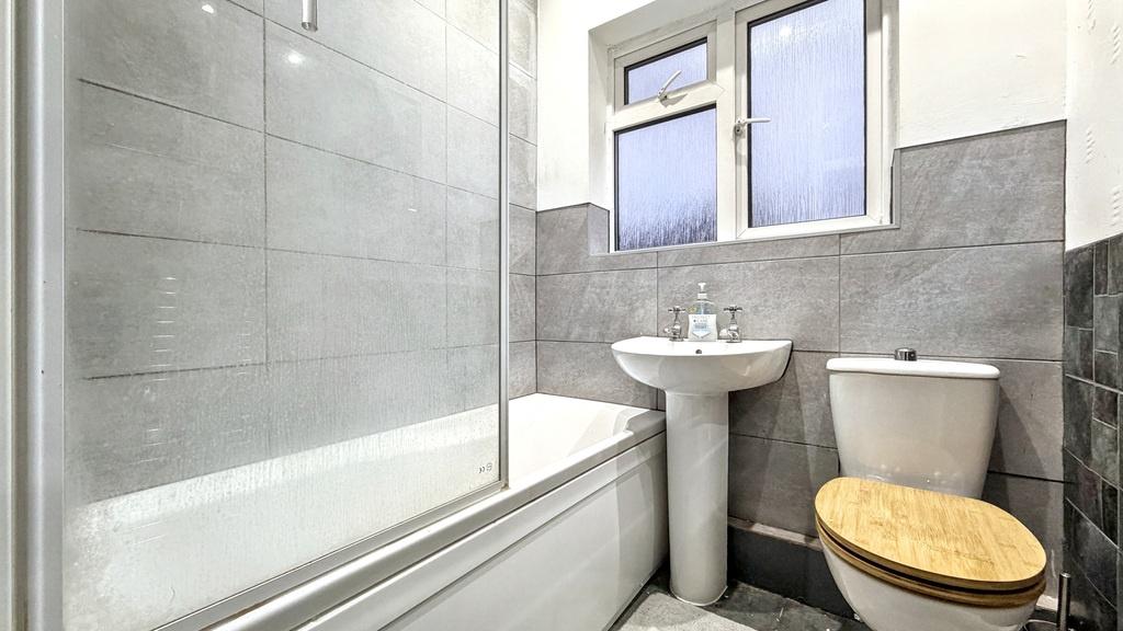 Bright, modern bathroom with a tiled bath and s...