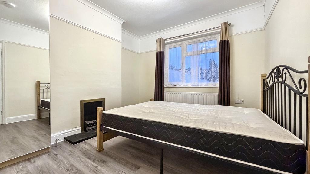 Bright, neutrally decorated bedroom with hardwo...