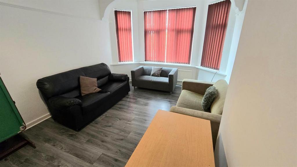 Bright furnished living area with a bay window,...