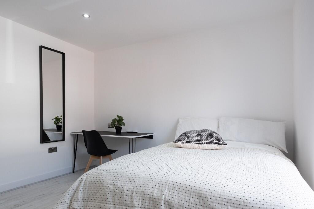 A bright and tidy bedroom featuring a comfortab...