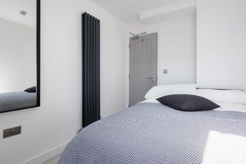 A tidy and well-lit single bedroom featuring a ...