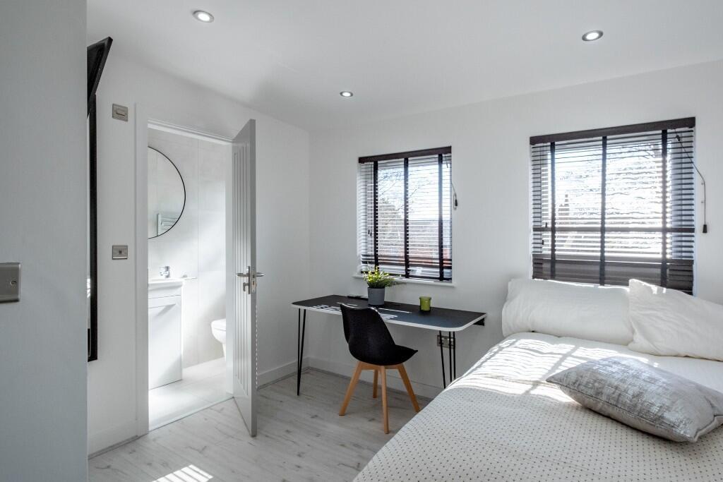 Bright and airy bedroom with large windows, a c...