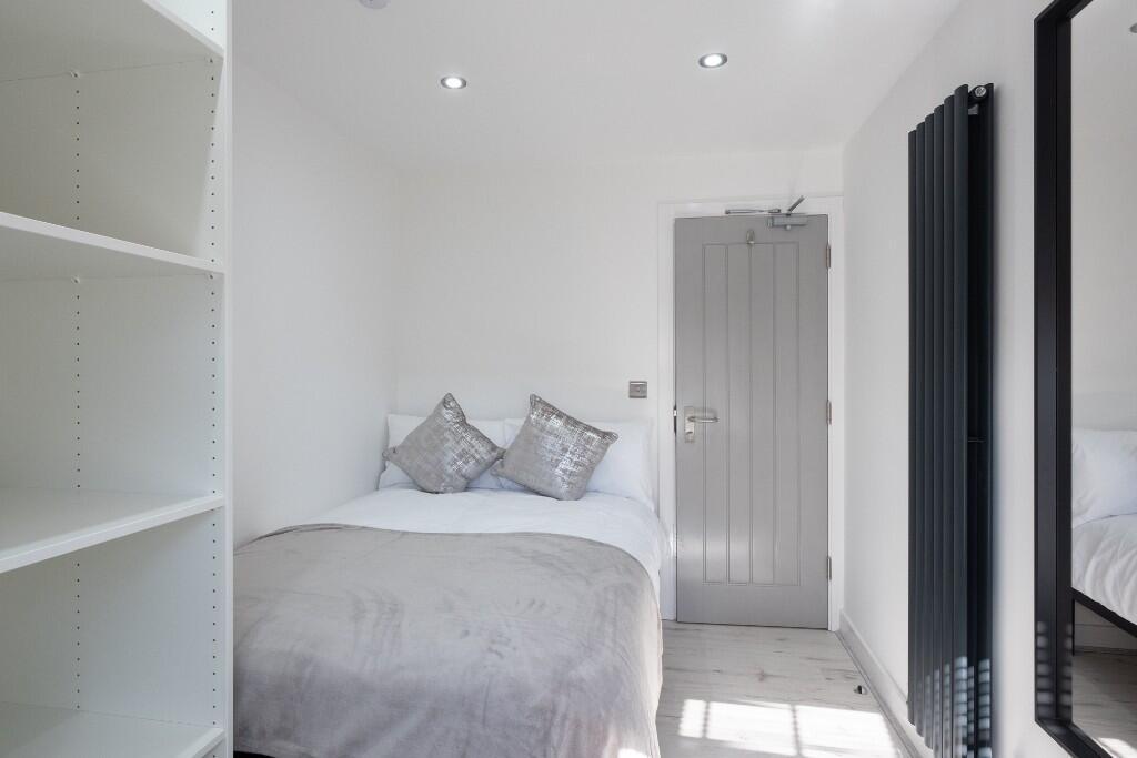 A bright and clean bedroom with a cozy double b...