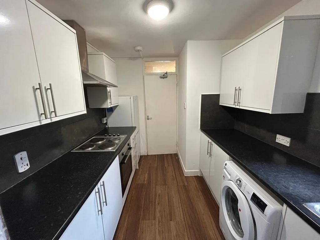 Bright, modern galley kitchen with white cabine...