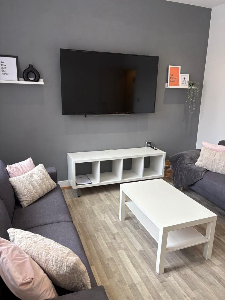 Bright, modern living room with grey feature wa...
