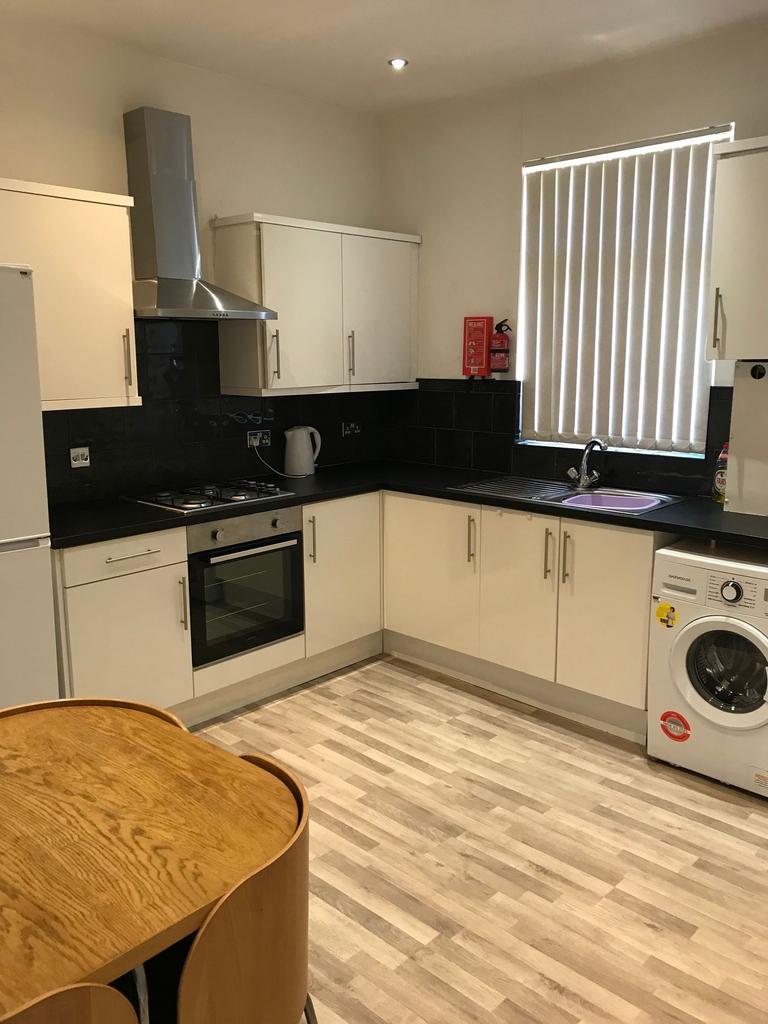 Modern fitted kitchen with white cabinets, blac...