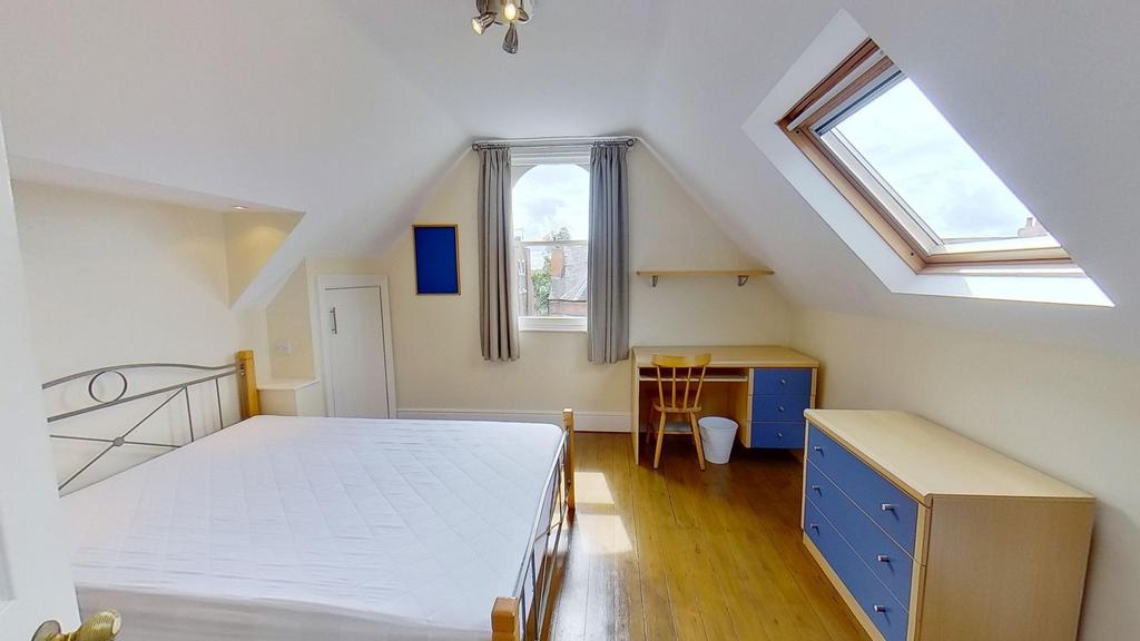 Bright attic double bedroom with a metal-framed...