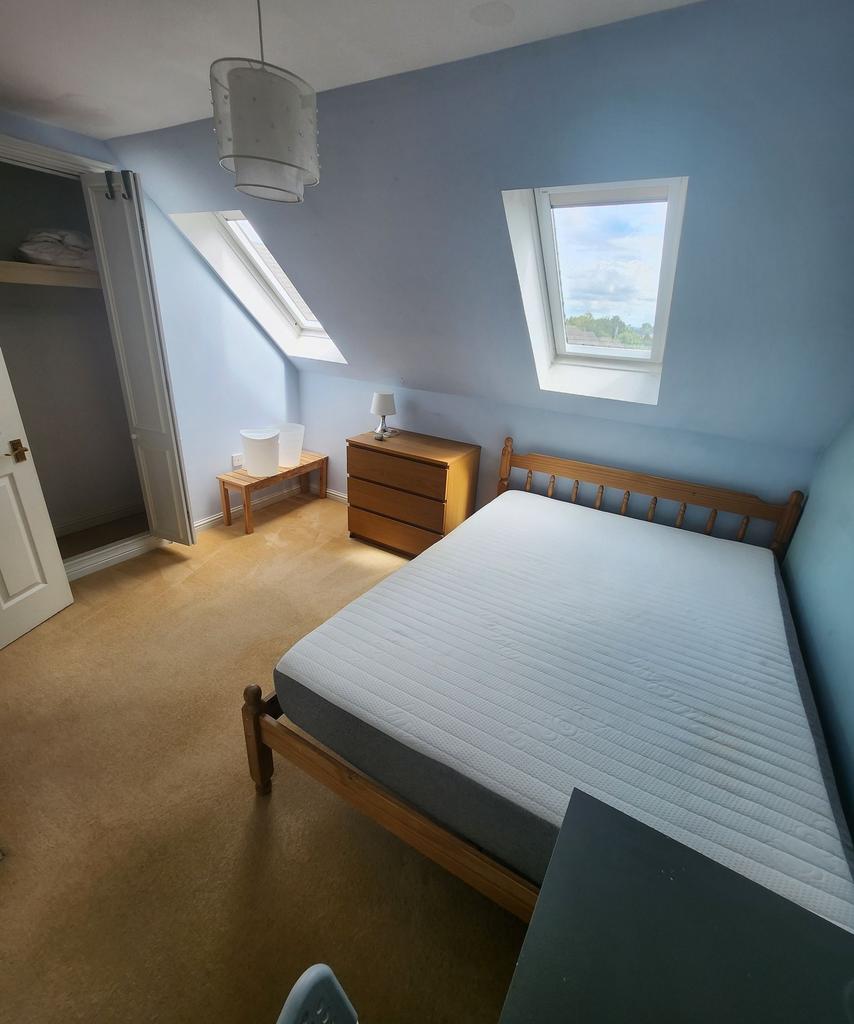 A cozy student bedroom featuring a wooden bed f...