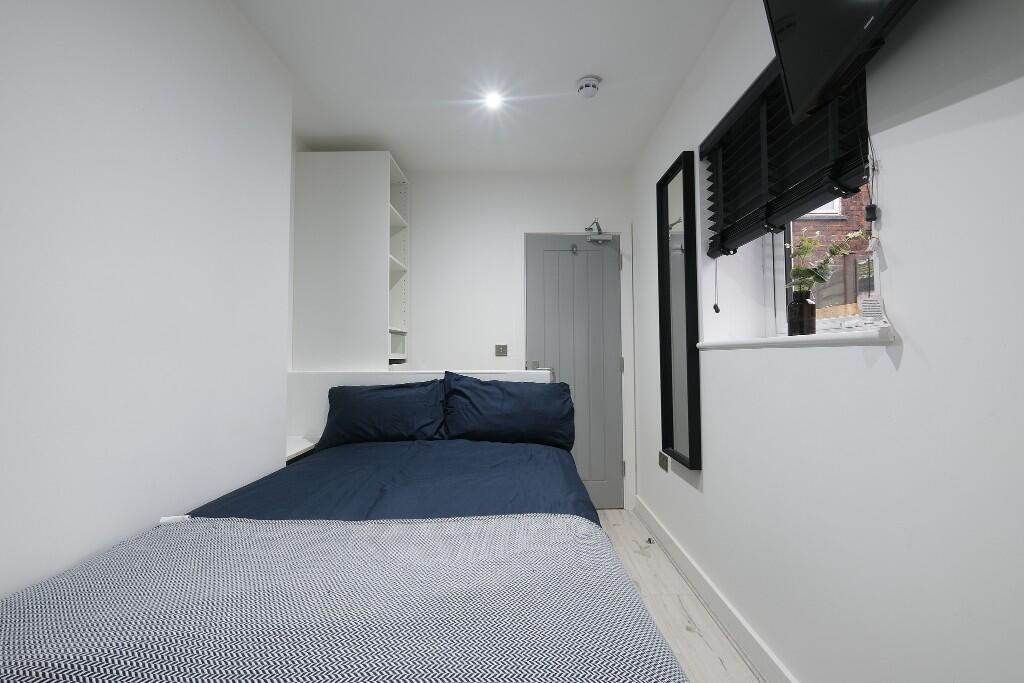 A bright and tidy bedroom with a comfortable do...