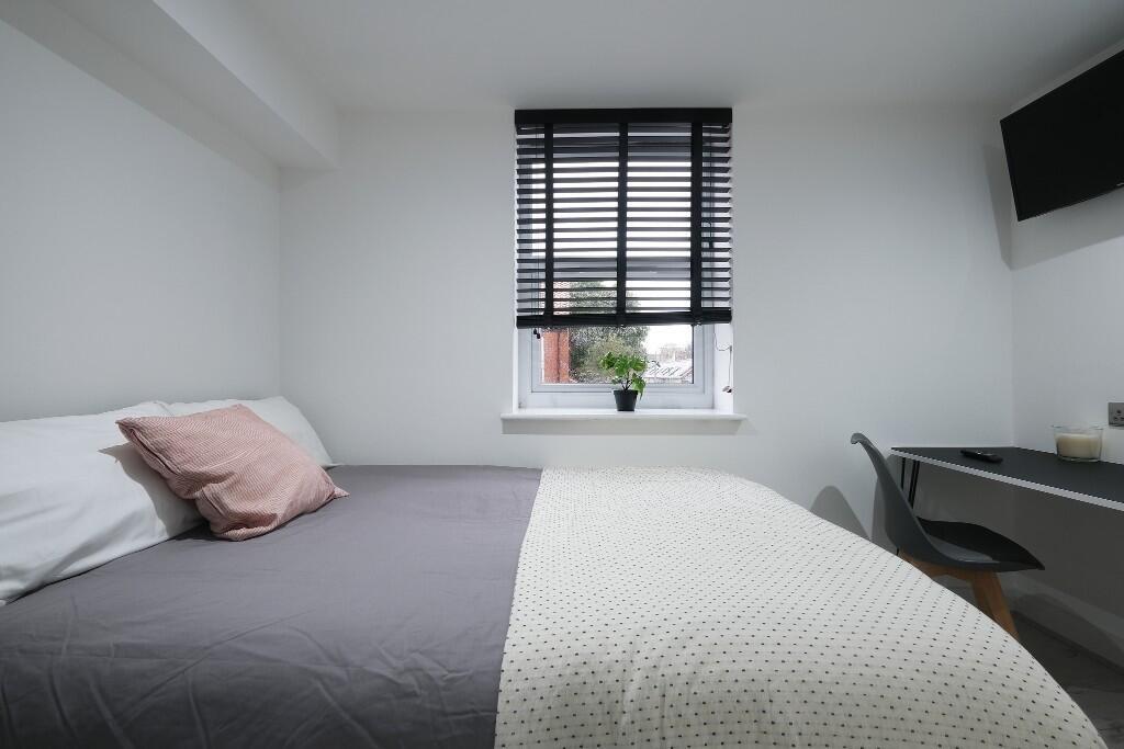 A modern, well-lit bedroom featuring a comforta...