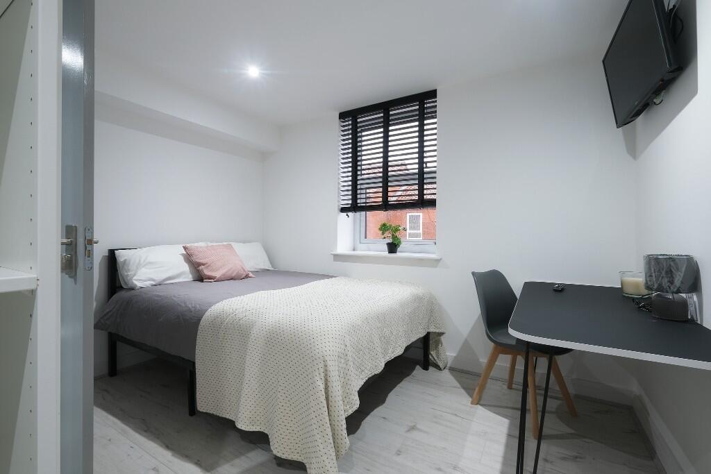 A bright and tidy bedroom featuring a comfortab...